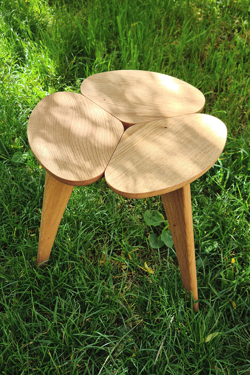 Le tabouret Farouch en chataîgnier pos&eacute; dans l'herbe.
